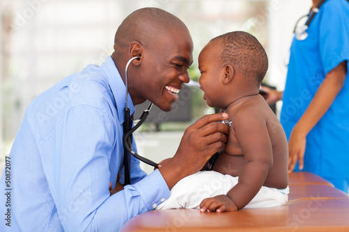 Photo: happy african male doctor examining baby boy happy african male doctor examining baby boy