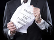 Businessman holding crumpled tax liability notice