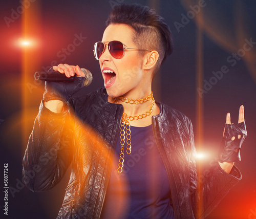 Photo: Rock diva is taking high notes while singing in microphone Rock diva is taking high notes while singing in microphone