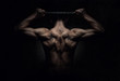 Muscular sports man stretching out over dark background