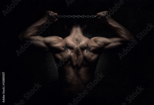 Photo: Muscular sports man stretching out over dark background Muscular sports man stretching out over dark background