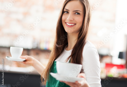 Photo: Waitress holding cups of coffee in cafe Waitress holding cups of coffee in cafe