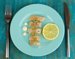 Dish of herring on plate on blue wooden table close-up