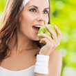 Woman in fitness wear with apple, outdoors