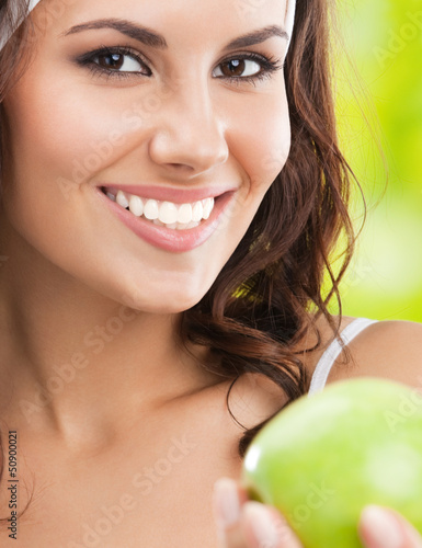 Photo: Woman in fitness wear with apple, outdoors Woman in fitness wear with apple, outdoors