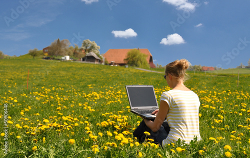 Photo: Girl with a laptop on the spring meadow Girl with a laptop on the spring meadow