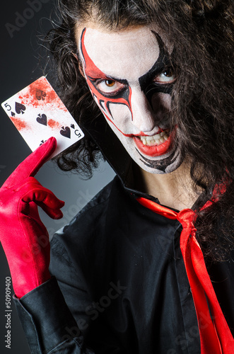 Photo: Evil clown with cards in dark room Evil clown with cards in dark room