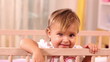 Adorable small girl standing in her bed and looking at camera