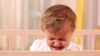 Small girl crying and standing in her bed