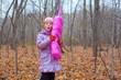 A little girl playing with a pink phone in autumn forest