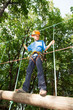 Young guy with equipment climber moves on balk holding ropes.