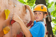 Young guy with climbed equipment on top of climbing wall.