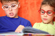 Girl and boy with glasses reading a book intently