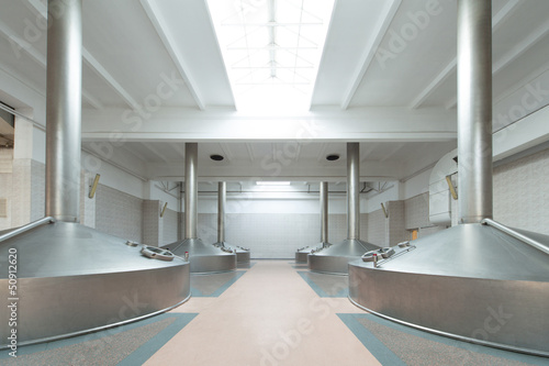 Photo: Equipment for the brewery. Shiny tanks in white room Equipment for the brewery. Shiny tanks in white room