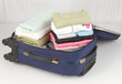 An opened suitcase packed with a lot of colorful cloths