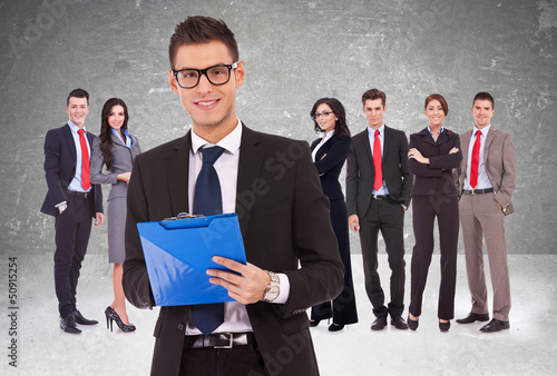 Photo: Leader holding a clipboard with business team behind Leader holding a clipboard with business team behind