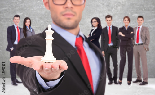 Photo: leader of a businessteam holding the white king of chess leader of a businessteam holding the white king of chess