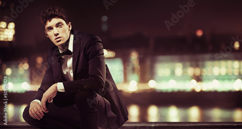 Photo: Stylish man with night town over the background Stylish man with night town over the background