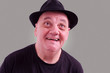 homme âgé avec chapeau et grand sourire sur fond gris