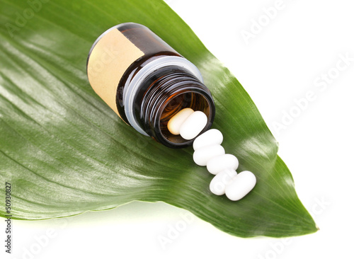 Photo: tablets on green leaf with bottle isolated on white tablets on green leaf with bottle isolated on white