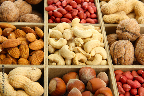 Photo: assortment of tasty nuts in wooden box, close up assortment of tasty nuts in wooden box, close up