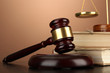 Golden scales of justice, gavel and books on brown background