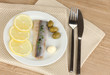 Dish of herring and lemon on plate on wooden table close-up