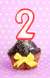 Photo: Birthday cupcake with chocolate frosting on lilac background Birthday cupcake with chocolate frosting on lilac background