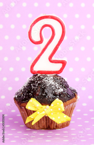 Photo: Birthday cupcake with chocolate frosting on lilac background Birthday cupcake with chocolate frosting on lilac background