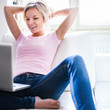 Foto : Pretty young woman using her laptop while relaxing on a sofa Pretty young woman using her laptop while relaxing on a sofa