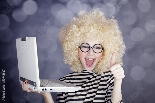 Photo: Portrait of funny girl in blonde wig with laptop. Studio shot. Portrait of funny girl in blonde wig with laptop. Studio shot.