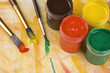 Paints and brushes against painted multicolored background