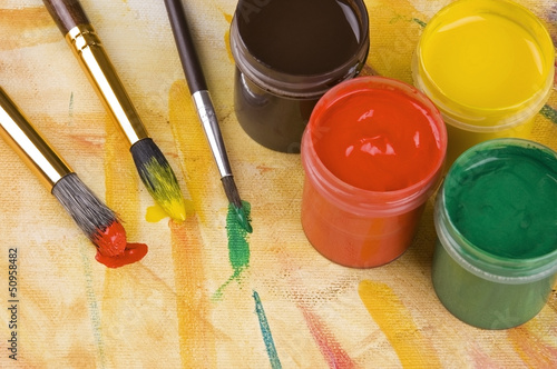 Photo: Paints and brushes against painted multicolored background Paints and brushes against painted multicolored background