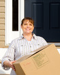 Woman carrying box on moving day in front of home