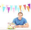 Smiling birthday guy with a party hat and a cake