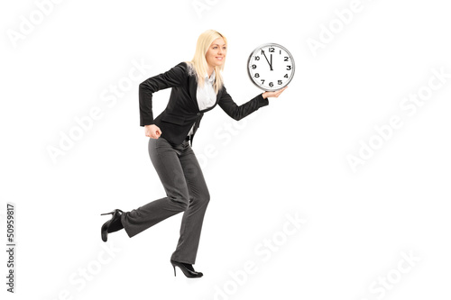 Photo: Full length portrait of a businesswoman running with clock Full length portrait of a businesswoman running with clock