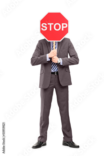 Photo: Full length portrait of a man in suit covering his face with a s Full length portrait of a man in suit covering his face with a s