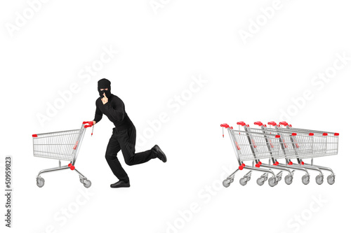 Photo: Full length portrait of a robber stealing an empty pushcart Full length portrait of a robber stealing an empty pushcart