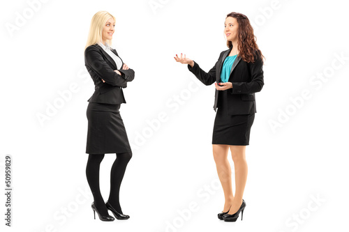 Photo: Full length portrait of a young professional women having a conv Full length portrait of a young professional women having a conv