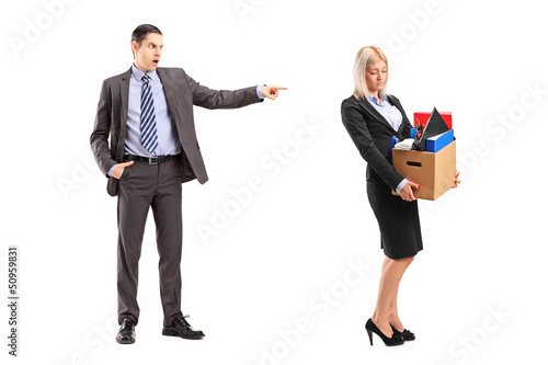 Photo: Full length portrait of an angry boss firing a woman with a box Full length portrait of an angry boss firing a woman with a box