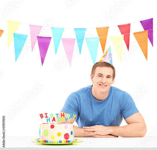 Photo: Smiling birthday guy with a party hat and a cake Smiling birthday guy with a party hat and a cake
