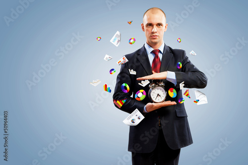 Photo: Business man holding alarmclock Business man holding alarmclock
