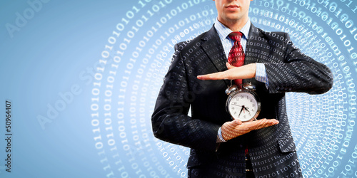 Photo: Business man holding alarmclock Business man holding alarmclock