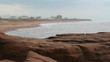 Misty beach on grey day with red rocks in the foreground.  PEI.