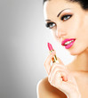 Beautiful woman applying pink lipstick on lips