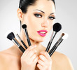 Beautiful woman with makeup brushes