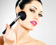 Beautiful woman applying blusher on face