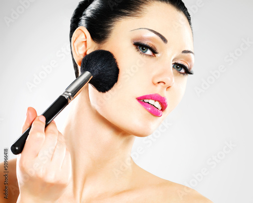 Photo: Beautiful woman applying blusher on face Beautiful woman applying blusher on face