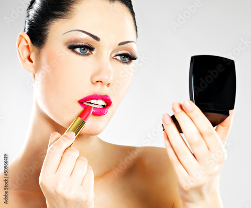 Photo: Beautiful woman applying pink lipstick on lips Beautiful woman applying pink lipstick on lips