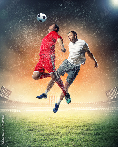 Photo: two football players striking the ball two football players striking the ball